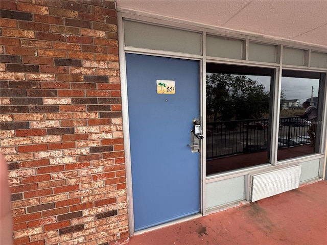 doorway to property with brick siding and visible vents