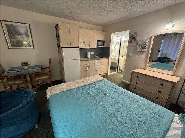 bedroom with a textured ceiling, a textured wall, connected bathroom, a sink, and freestanding refrigerator