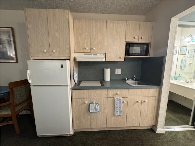 kitchen featuring light brown cabinetry, a sink, freestanding refrigerator, and under cabinet range hood