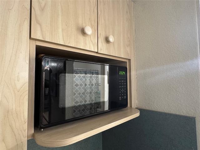 interior details featuring black microwave and a textured wall