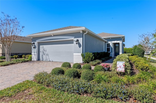 single story home with a garage, decorative driveway, and stucco siding