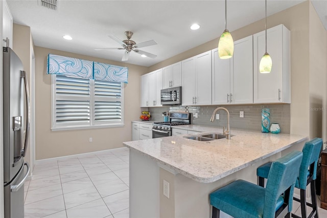 kitchen with a peninsula, appliances with stainless steel finishes, white cabinets, and a sink