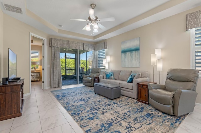 living area with visible vents, baseboards, a ceiling fan, marble finish floor, and a raised ceiling