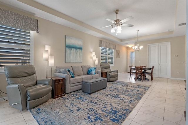 living area with a raised ceiling, visible vents, marble finish floor, and baseboards