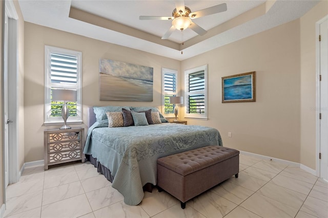 bedroom with multiple windows, a raised ceiling, and baseboards