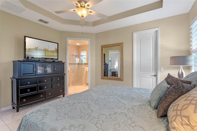 bedroom featuring baseboards, visible vents, a tray ceiling, and ensuite bathroom