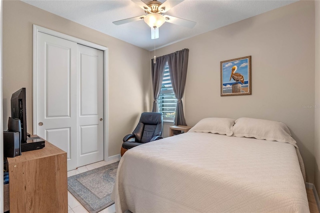 bedroom with ceiling fan, a closet, light tile patterned flooring, and baseboards