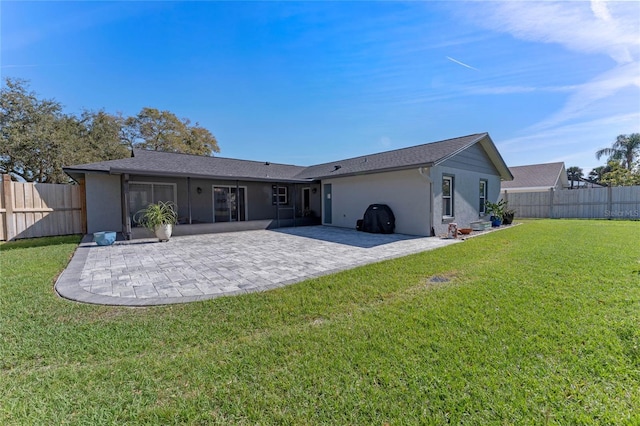 rear view of house featuring a yard, a patio area, a fenced backyard, and stucco siding