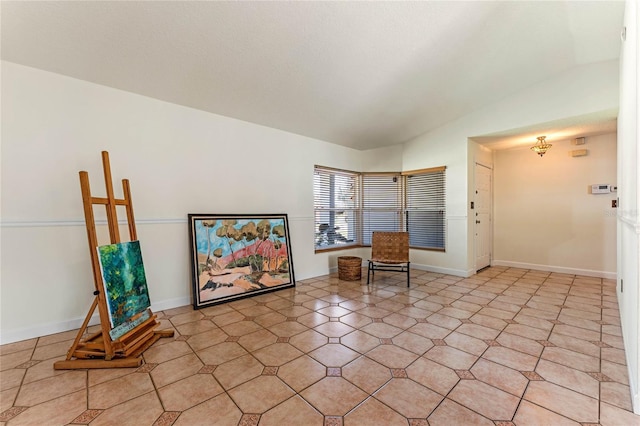 unfurnished room featuring lofted ceiling and baseboards