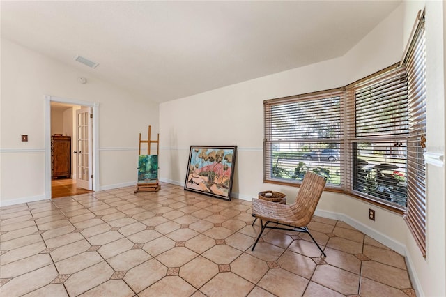 unfurnished room with lofted ceiling, baseboards, and visible vents