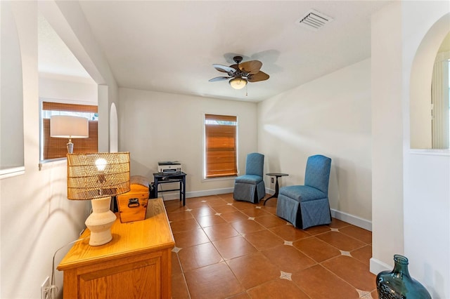 living area featuring arched walkways, a ceiling fan, baseboards, visible vents, and tile patterned floors