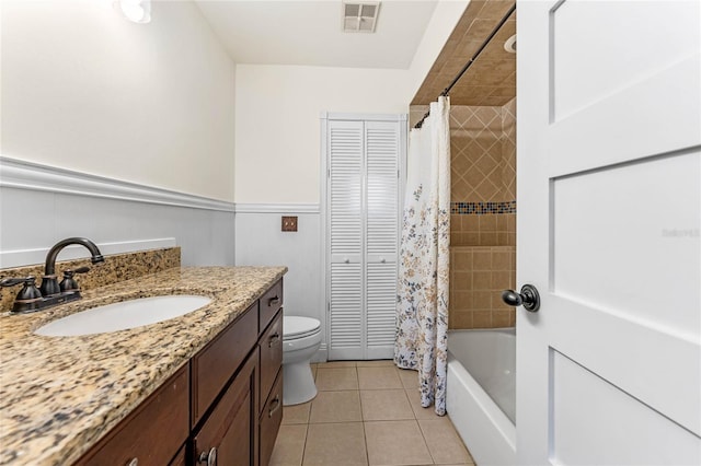 bathroom with tile patterned flooring, a wainscoted wall, vanity, visible vents, and a closet