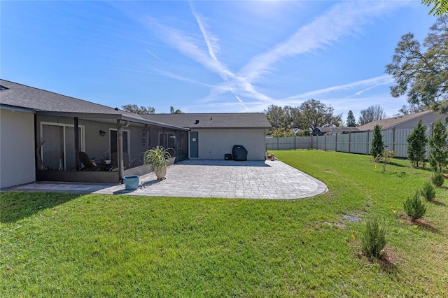 back of house featuring a yard, a patio, stucco siding, a sunroom, and fence