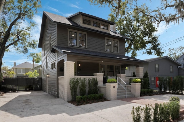 american foursquare style home with a porch, brick siding, and fence