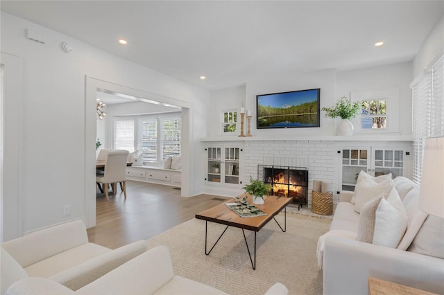 living room featuring a brick fireplace, wood finished floors, and recessed lighting