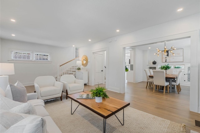 living room featuring recessed lighting, plenty of natural light, light wood finished floors, and stairs