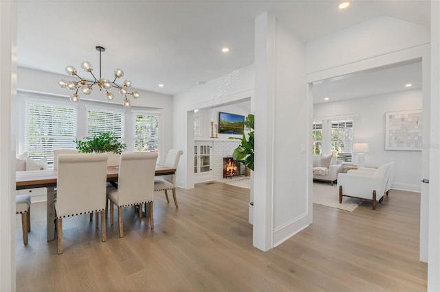 dining area with a notable chandelier, a fireplace, wood finished floors, and recessed lighting