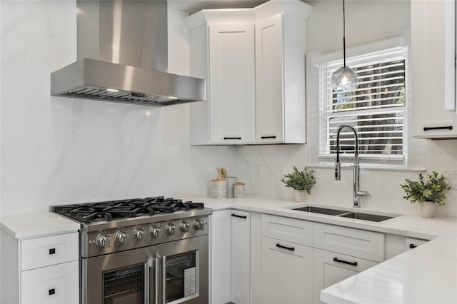 kitchen with white cabinetry, stainless steel range, wall chimney range hood, and a sink