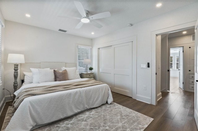 bedroom with dark wood-type flooring, a closet, multiple windows, and baseboards