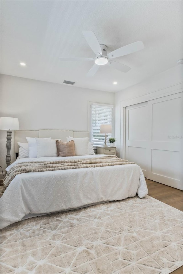 bedroom featuring recessed lighting, wood finished floors, visible vents, a ceiling fan, and a closet