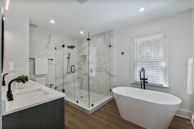 bathroom featuring a freestanding tub, wood finished floors, a sink, visible vents, and a marble finish shower