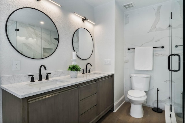 full bathroom with a marble finish shower, visible vents, a sink, and toilet