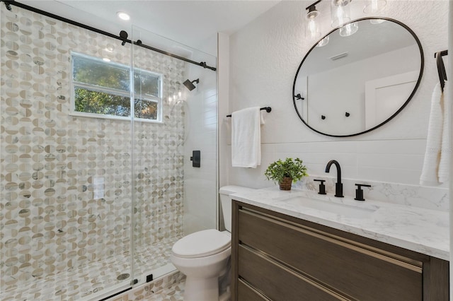 bathroom with tile walls, visible vents, toilet, a stall shower, and vanity