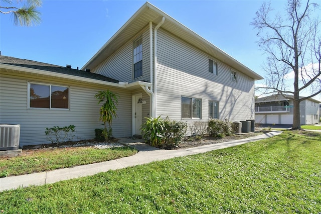 view of side of property with central AC and a lawn