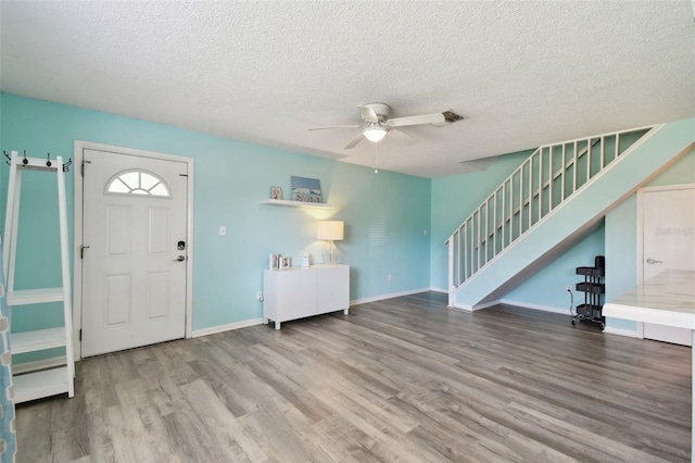 entrance foyer with baseboards, ceiling fan, wood finished floors, stairs, and a textured ceiling