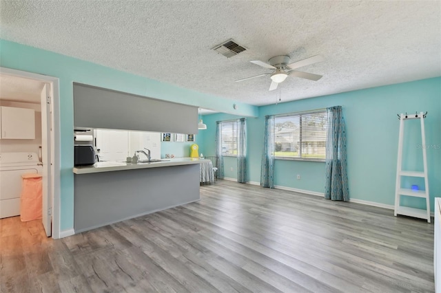 kitchen featuring visible vents, ceiling fan, wood finished floors, and washer / dryer