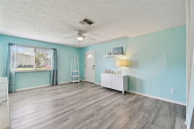 interior space featuring a ceiling fan, wood finished floors, visible vents, and baseboards