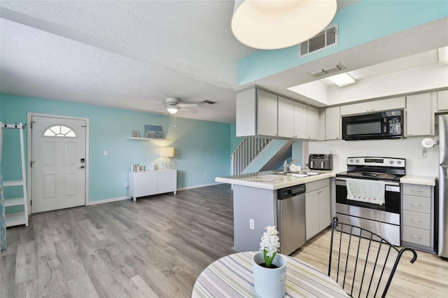 kitchen with light wood-type flooring, visible vents, appliances with stainless steel finishes, and a sink