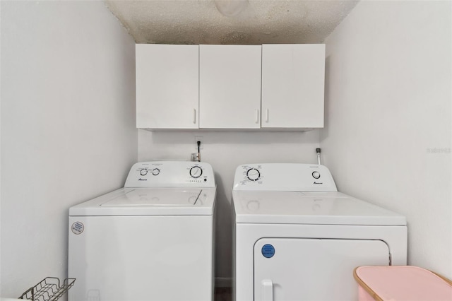 washroom featuring washer and dryer, cabinet space, and a textured ceiling