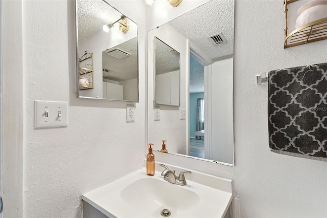 bathroom with visible vents, a textured ceiling, and a textured wall