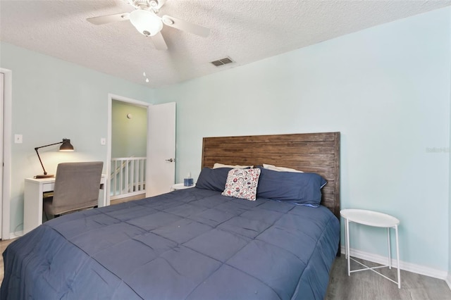 bedroom featuring a ceiling fan, baseboards, visible vents, and a textured ceiling