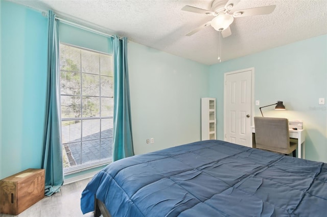 bedroom with a ceiling fan, a textured ceiling, and wood finished floors