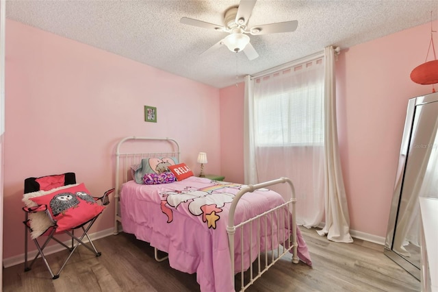 bedroom with a textured ceiling, ceiling fan, wood finished floors, and baseboards