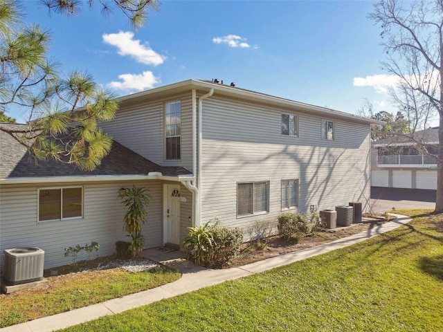 back of house with central AC unit and a yard