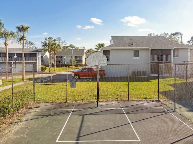 view of sport court with a residential view, fence, and a yard