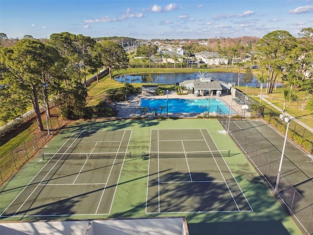 view of sport court featuring a patio, a water view, fence, and a community pool