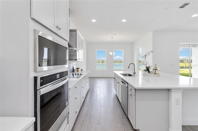 kitchen with a sink, visible vents, stainless steel dishwasher, and light countertops