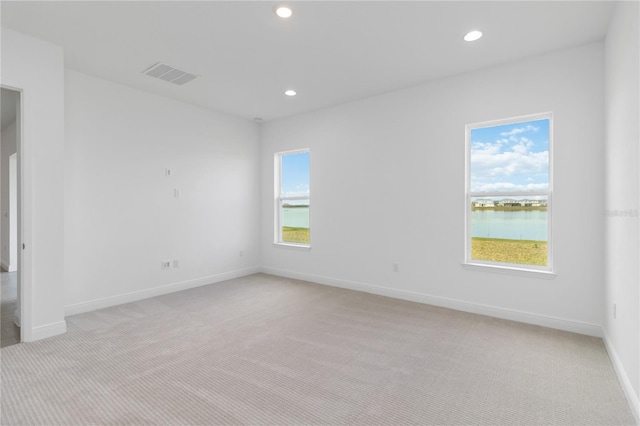 empty room featuring light carpet, recessed lighting, visible vents, and baseboards