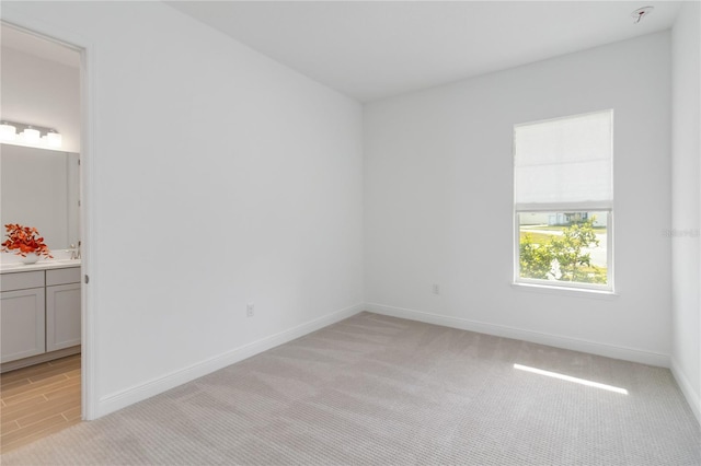 unfurnished room with light colored carpet and baseboards