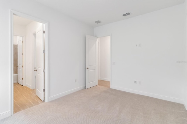 unfurnished bedroom featuring baseboards, visible vents, and light carpet