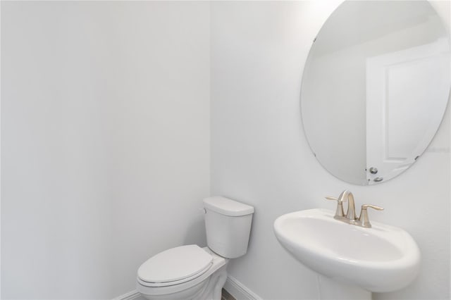 bathroom with toilet, baseboards, and a sink