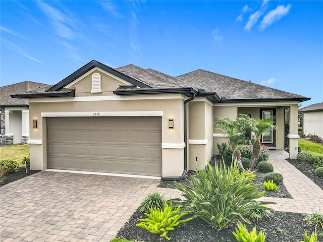 view of front of house featuring a garage, a shingled roof, decorative driveway, and stucco siding