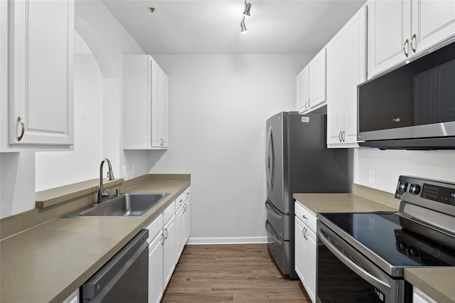 kitchen with baseboards, dark wood-style floors, appliances with stainless steel finishes, white cabinetry, and a sink