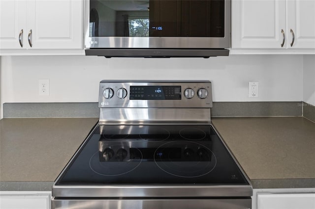 kitchen featuring dark countertops, appliances with stainless steel finishes, and white cabinets