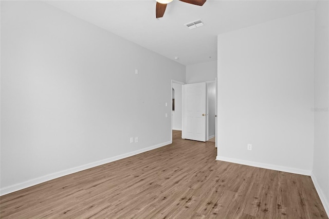 empty room featuring light wood-style floors, visible vents, baseboards, and a ceiling fan