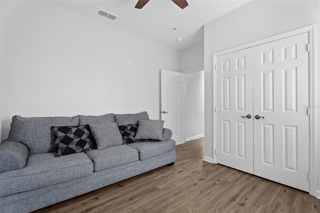 living area featuring baseboards, wood finished floors, visible vents, and a ceiling fan